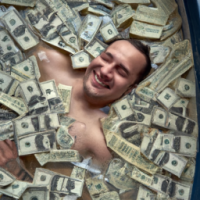 a man lies carefree in a bathtub full of dollar bills and coins